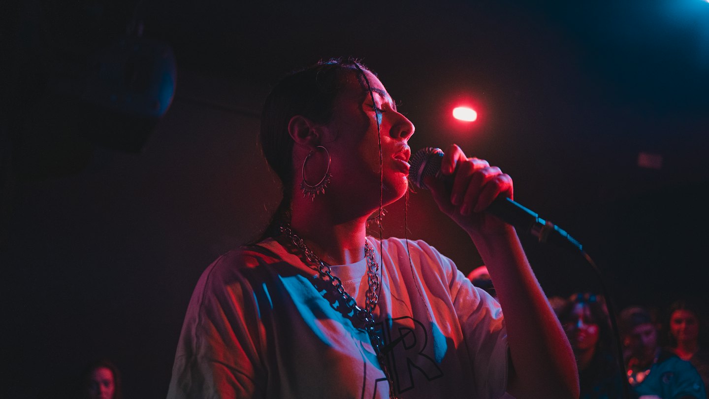 Singer performing into a microphone on a concert stage.