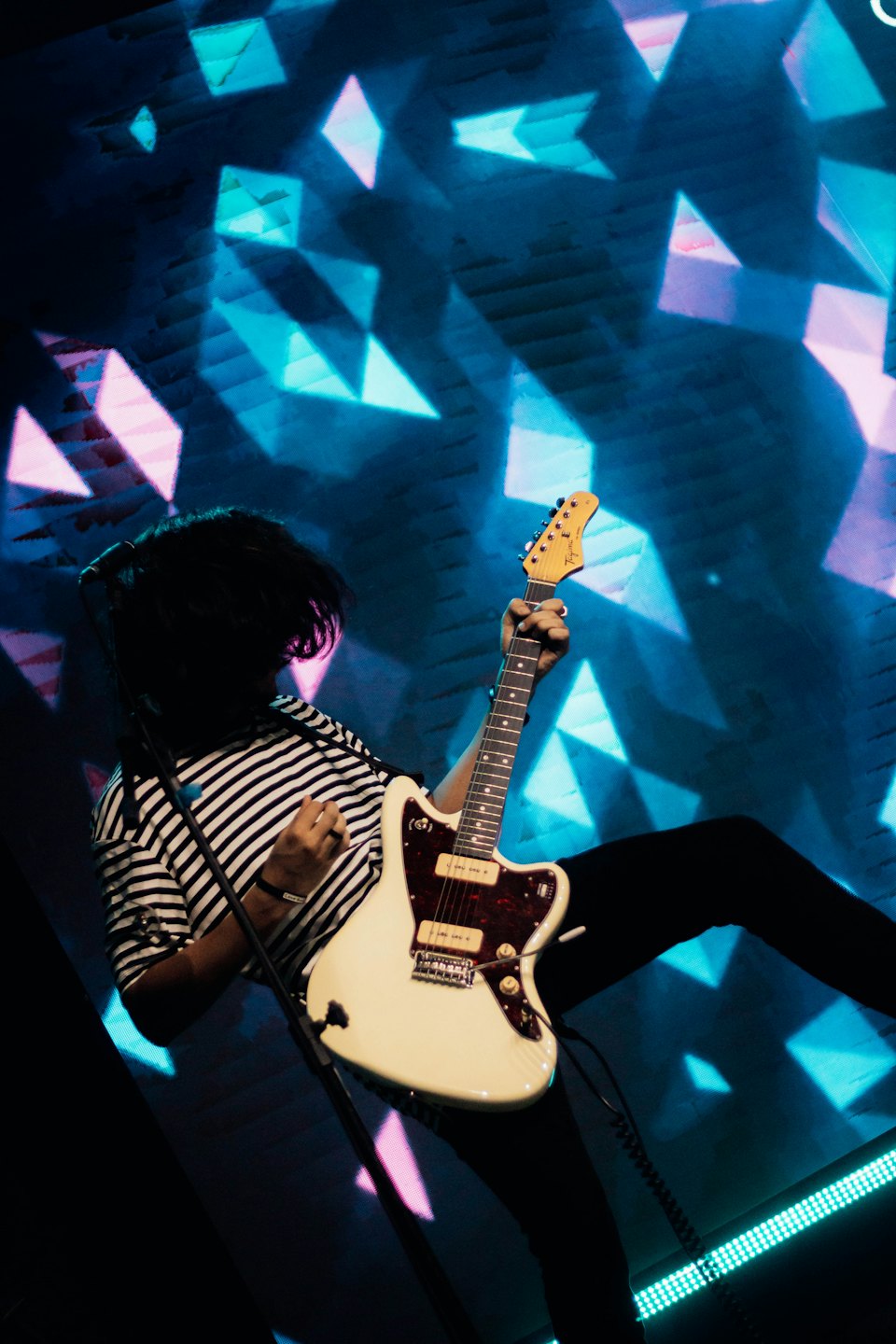 Musician playing a white electric guitar on stage.