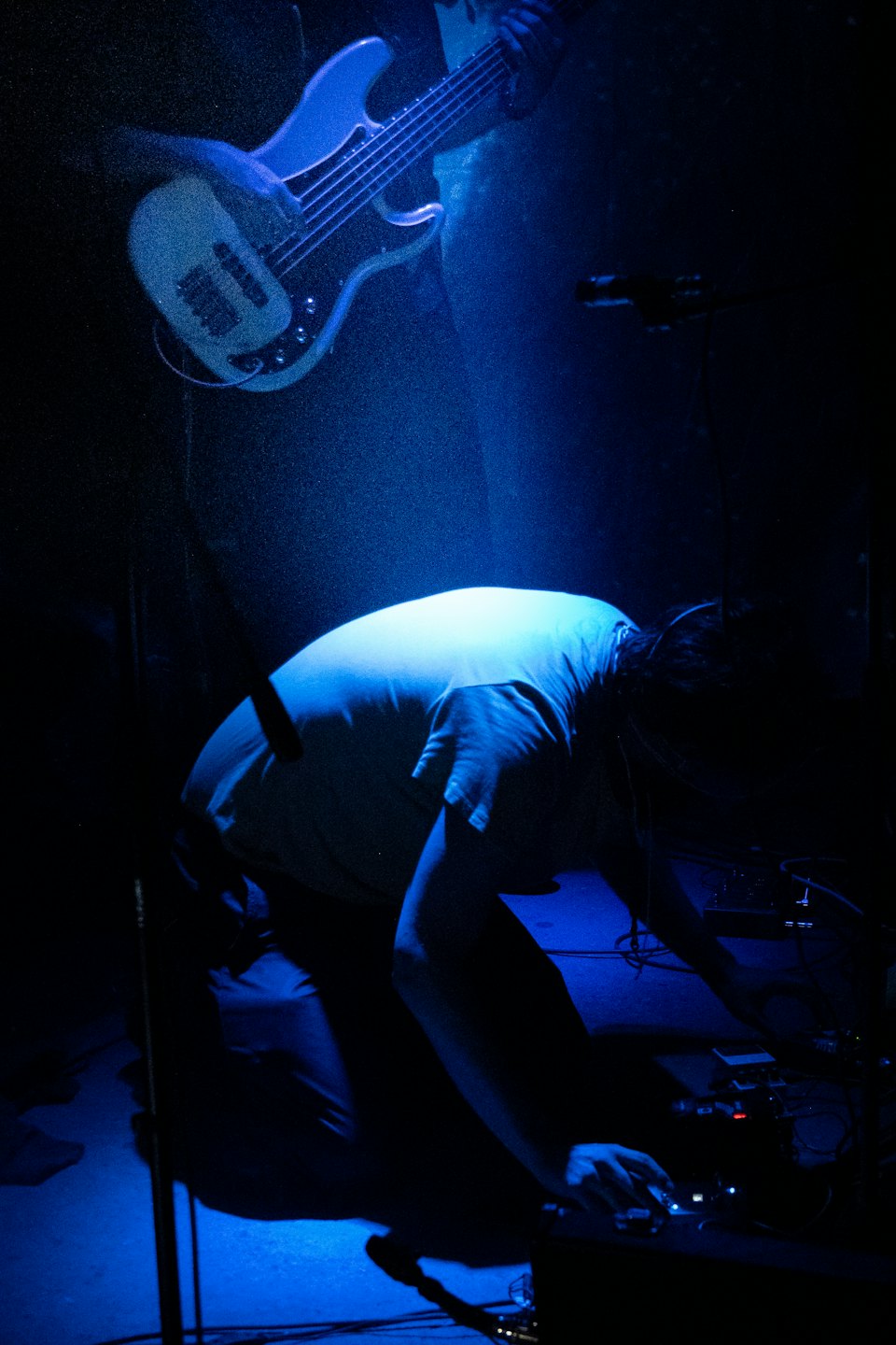 Two musicians performing on stage with electronic equipment.